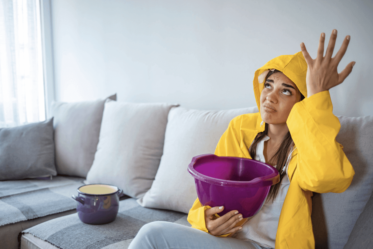 Young woman holding a bowl because of the roof leak